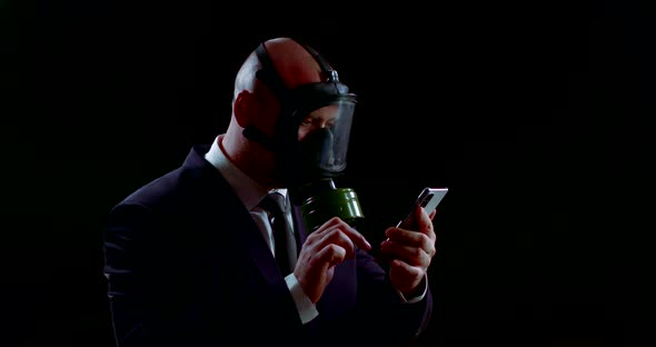 Portrait of a Man in a Business Suit and a Gas Mask on a Black Background