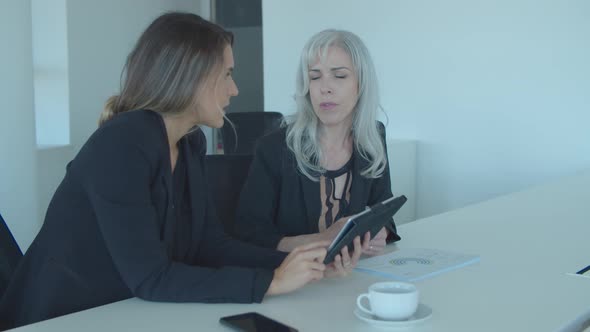 Two Businesswomen Discussing and Analyzing Reports