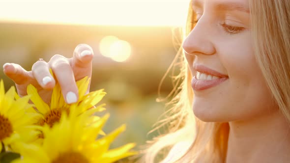 Girl Smells Bouquet of Sunflowers in the Field in Sunrays