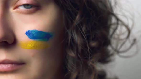 Close Up Of The Girl's Face. Flag Of Ukraine On The Cheek. Symbolizes Ukraine In Difficult Times
