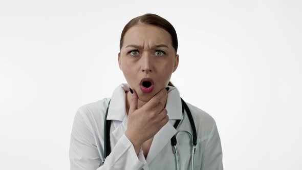 Caucasian Woman Doctor Is Very Surprised, Opens Her Mouth, Holds Chin with Hand