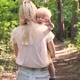 The camera follows a woman walking through the forest holding her son in her arms. - VideoHive Item for Sale
