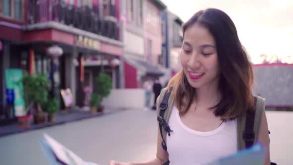 Young Asian backpacker woman direction and looking on location map while traveling at Chinatown.