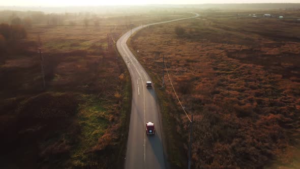 Two Retro Cars Drive Along a Winding Road in the Light of Sunrise or Sunset Late Autumn Shooting