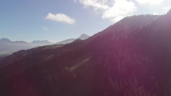 AERIAL: Pan shot of landscape of the alps with mountains and forest