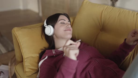 Close Up of Young Happy Woman Lying on Sofa and Listening to Music