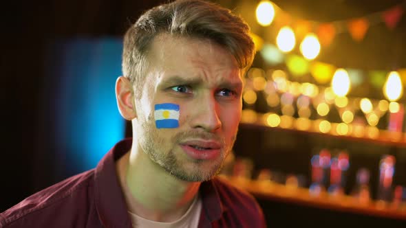 Football Fan With Argentinian Flag on Cheek Making Facepalm, Unhappy With Loss