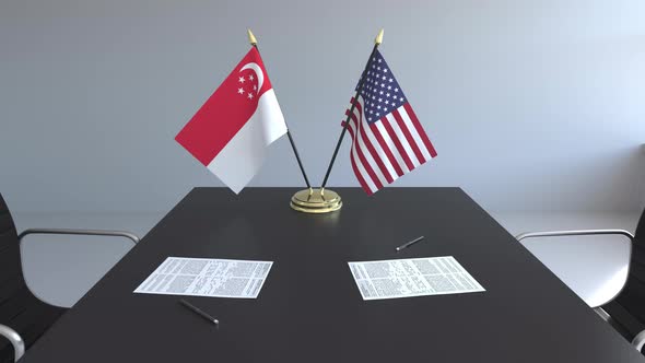 Flags of Singapore and the USA and Papers on the Table