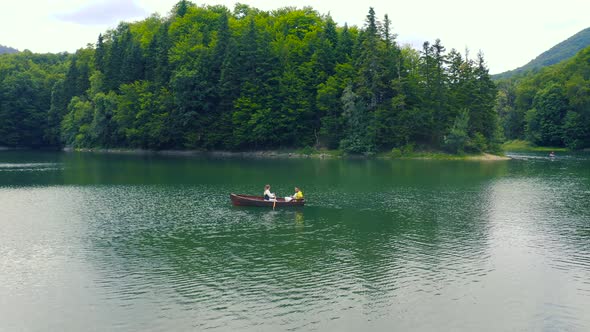 Young Couple are Sailing on a Old Wooden Boat in Lake