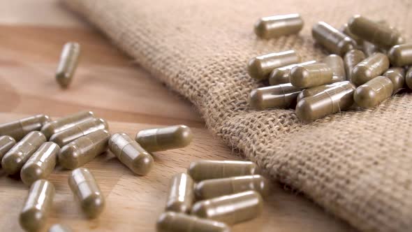 Falling medicinal capsules onto a rustic rough burlap and wooden surface