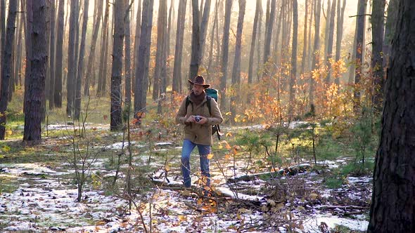 A Photographer with a Backpack and a Camera Walks in the Autumn Forest