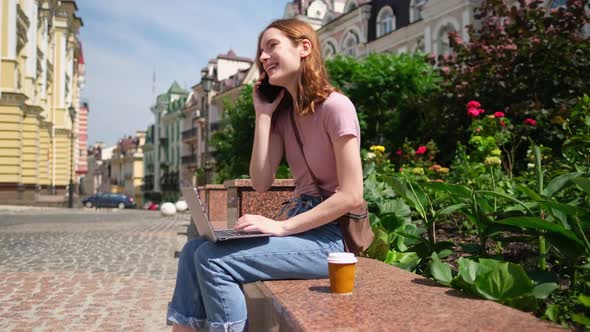 Beautiful Young Woman Tourist with Takeout Coffee in the City Center Using Laptop