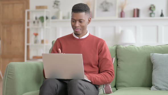 African Man doing Video Call on Laptop on Sofa