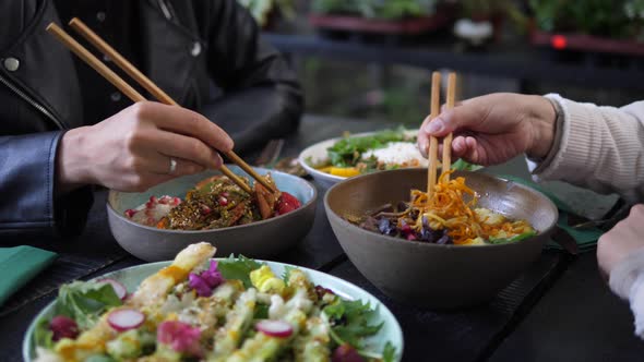 Two People with Chopsticks Enjoying Their Bowls Full of Healthy Meals in Asian Cuisine Style Dinner