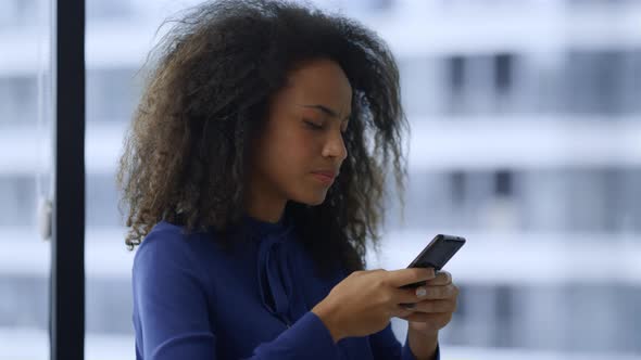 Focused African American Woman Executive Looking Mobile Phone in Workplace