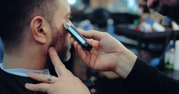Hairdresser Shaves the Beard to the Client with a Hair Clipper