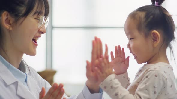 Asian Pediatrician Playing Hand Clapping Game with Toddler Girl