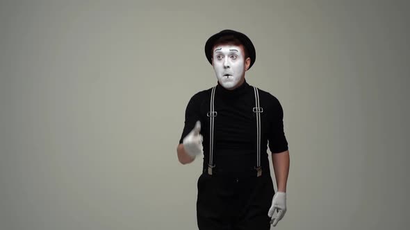 Portrait of Male Mime Flipping Imaginary Coin Remains Dissatisfied with Result and Flips Coin Again