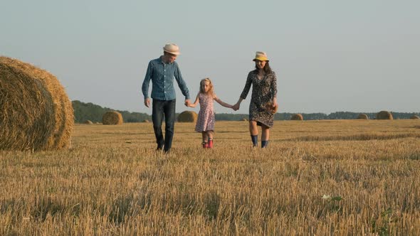 Family with Little Girl Walk in Harvested Field