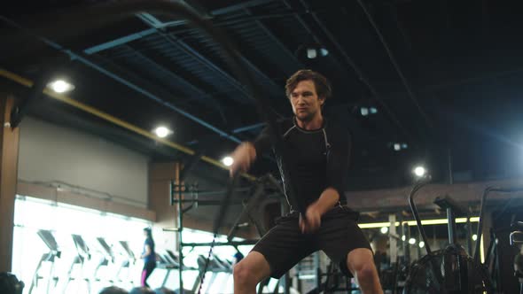 Focused Bodybuilder Using Battle Ropes in Sport Club. Athlete Exercising at Gym