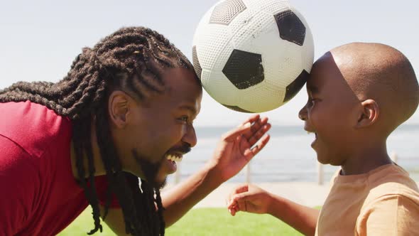 Video of happy african american father and son having fun with ball outdoors