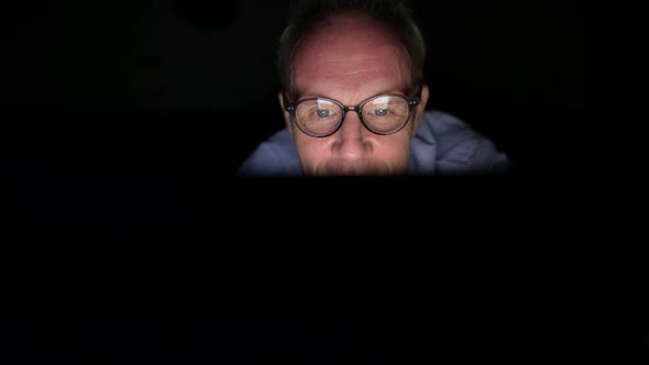 Mature Scandinavian Man Using Digital Tablet in Dark Room