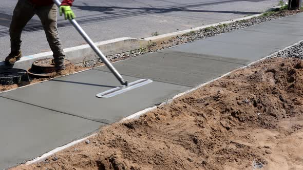 Mason Building a Screed Coat Cement a Laborer Floats a New Concrete Sidewalk