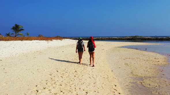 Sexy happy ladies travelling enjoying life on the beach on summer white sand and blue background 4K