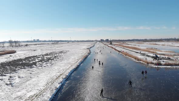 People ice skating on frozen canals in Netherlands, 4K winter aerial view