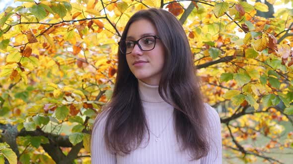 Portrait of Happy Teenage Girl in Front of Yellow Green Tree Foliage on a Bright Autumn Day, Close U