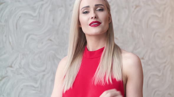 Stylish Elegant Blonde Woman in Home Living Room, Wearing Red Sexy Dress