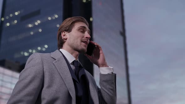Portrait of a Young Businessman Standing Near a Business Car and Talking on a Mobile Phone Top