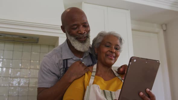 African american senior couple having a video call on digital tablet in the kitchen at home