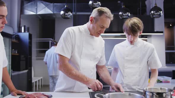 Professional Caucasian male chef wearing chefs whites in a restaurant kitchen teaching