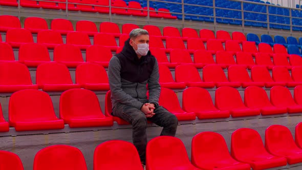 Young Man in Medical Mask Sitting on Stadium Bleachers Alone