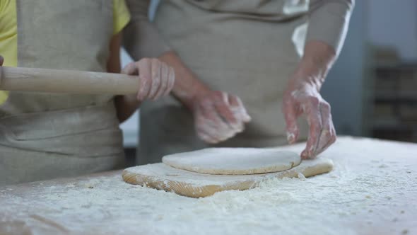 Hands of Female Kid Rolling Dough With Rolling Pin, Helping Granny to Cook