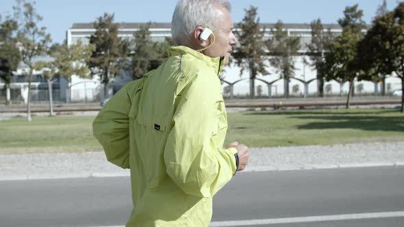 Active Male Pensioner with Hearing Aid Device Jogging Outside