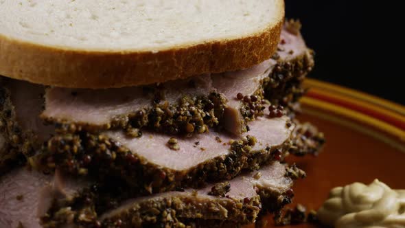 Rotating shot of delicious, premium pastrami sandwich next to a dollop of dijon mustard