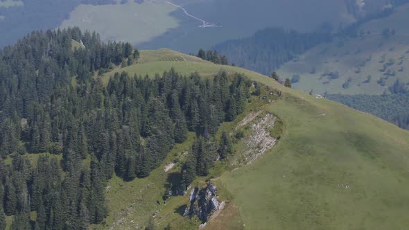 Drone shot of a hill with typical mountain farms ("alpages") in the background. Fribourg, Switzerlan