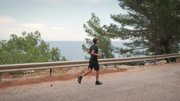 Young man jogging along coast in morning