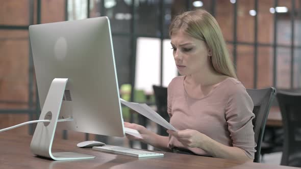 Upset Woman Reading Document on Office Desk