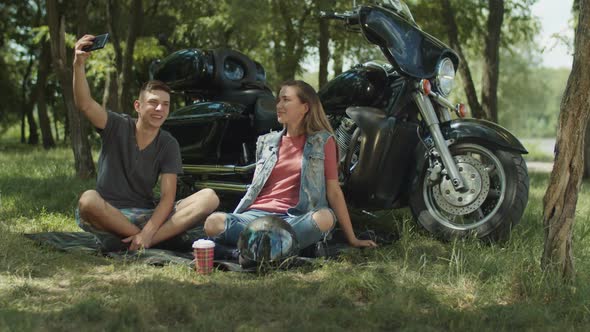 Joyful Couple Taking Selfie on Phone By Motorbike