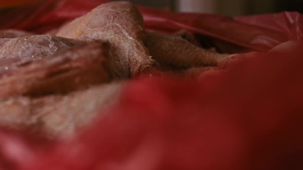 Closeup View of Hands in Gloves Packing Chicken Legs From a Box Into Individual Plastic Bags