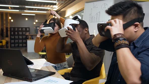 Young Business Team Wearing VR Virtual Reality Glasses for Work with Laptop in the Stylish Office