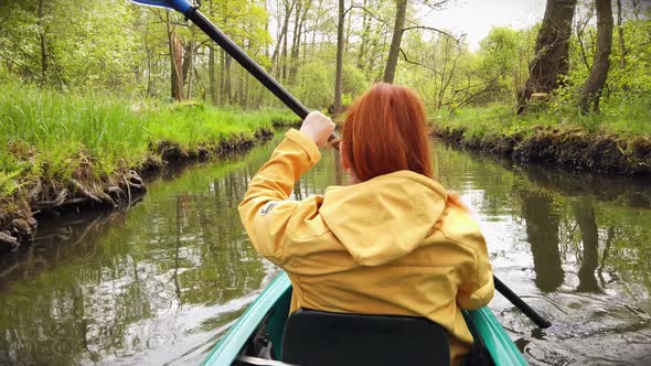 Outdoor Woman with Yellow Coat in Kayak on a River in Stunning Nature