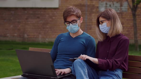 Two professional coworkers in protective mask discuss