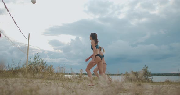 Young Sporty Women Are Playing Beach Volleyball on Open Sandy Court at Summer Day, Players Are