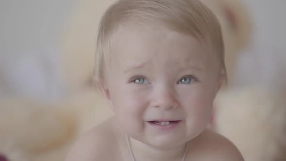 Close-up Portrait Toddler Sitting Playing with a Jar in the Kitchen. Cute Caucasian Baby Indoors.