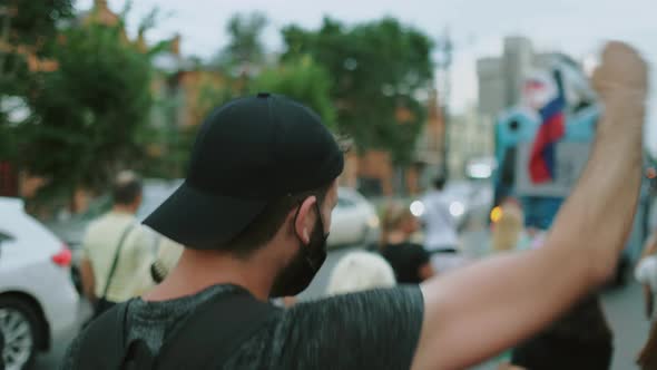 Protester Person Waves Arm Fist in Rioting Rally Crowd Under Covid Restrictions