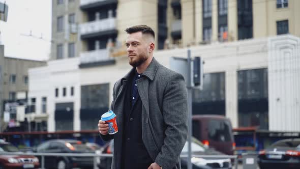 Man with coffee cup outdoor. Young businessman walking through city street and holding takeaway coff